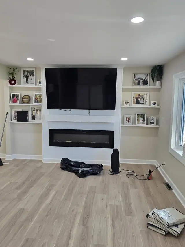 Living room wall with built-in white shelves around a TV and a linear electric fireplace